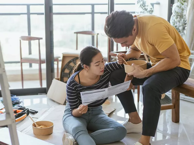 Home Ownership - A young couple reading a manual in the midst of remodeling their home by doing it themselves