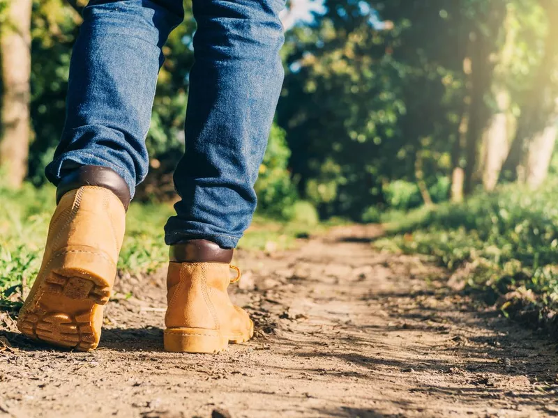 Man wearing boots walking in a green forest