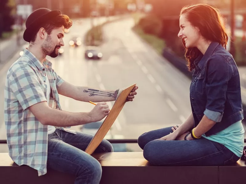 Painter drawing a portrait of his girlfriend at a bridge