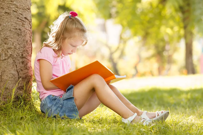 Cute little girl is reading a book