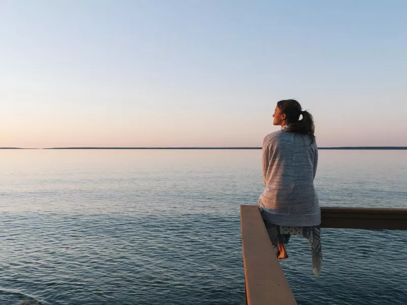 Young woman sitting on edge looks out at view