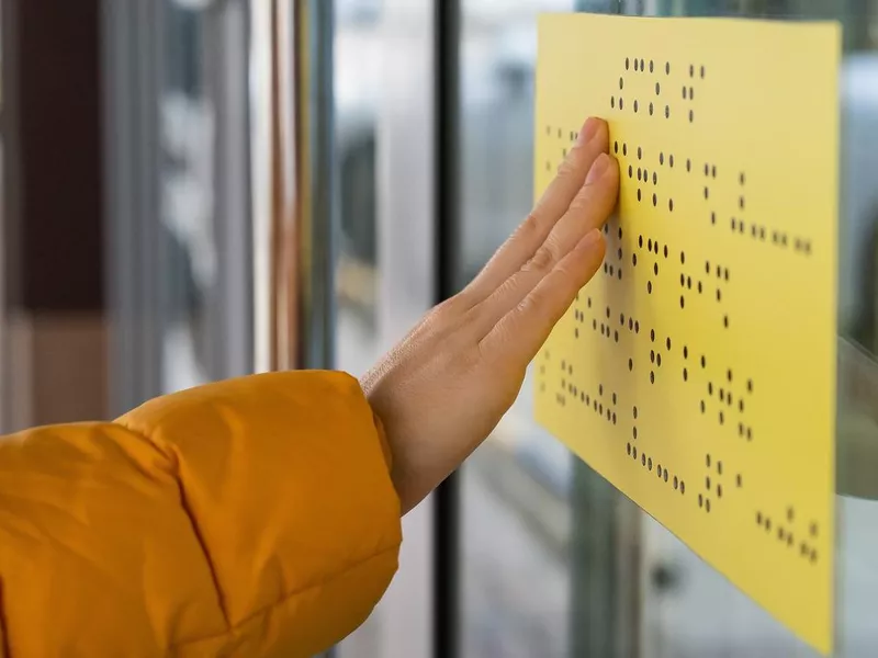 Close-up of a woman reading a braille lettering on a glass door