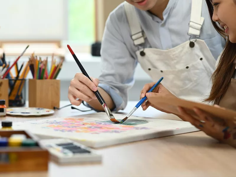 Cropped shot of loving couple painting on canvas at art studio. Leisure activity, creative hobby and art concept.