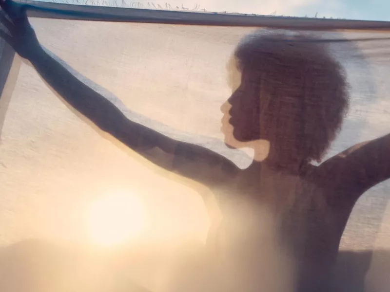 Silhouette of woman behind curtain in sunset on the beach