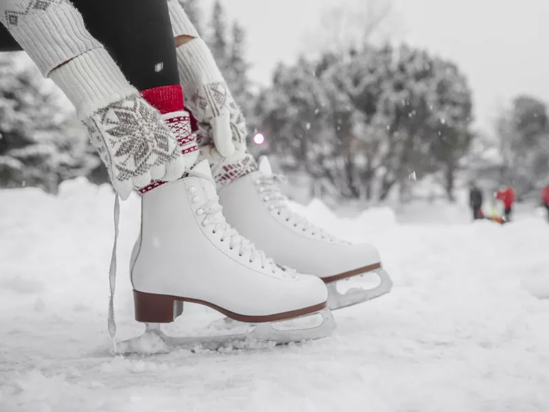 Ice skating woman getting ready lacing leather skates boots to go skate at outside rink nature park. Winter sport fun active lifestyle.