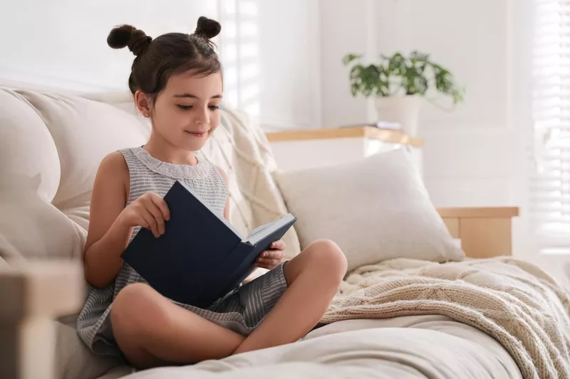 Little girl reading fairy tale in living room