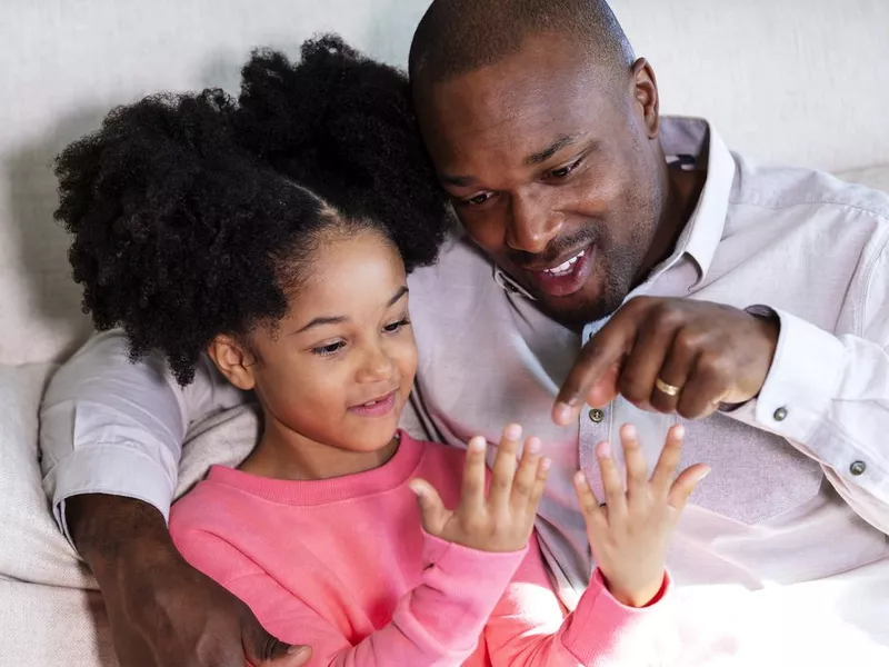 Father, girl on couch counting fingers