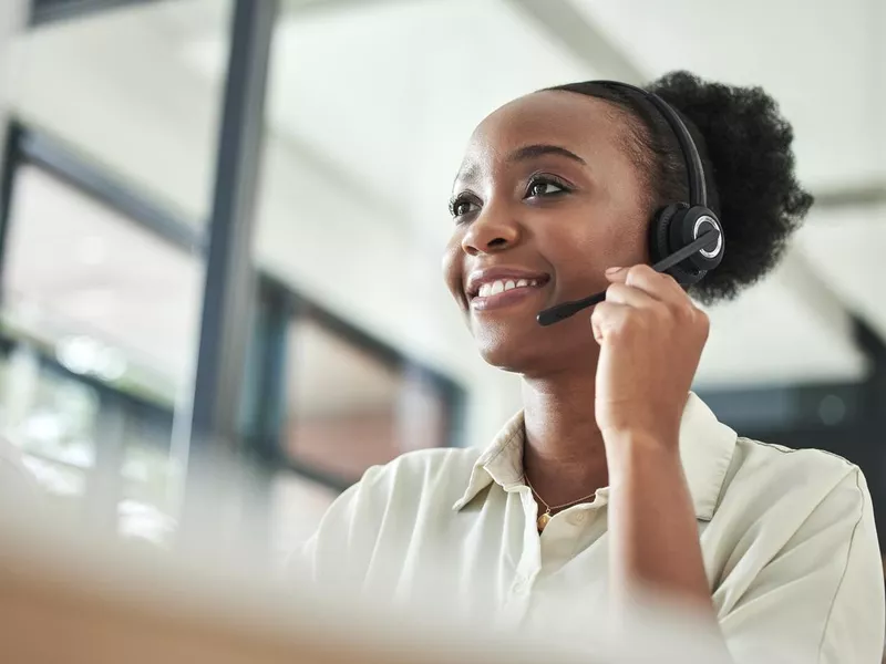 Low angle shot of an attractive young call centre agent sitting alone in the office and using her computer