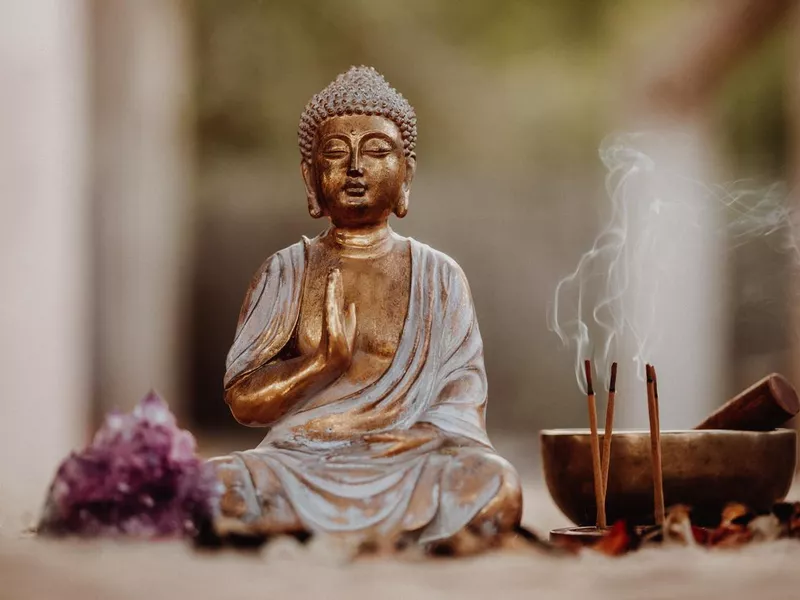 Close up of a Buddha figurine and smoky incense with gong and amethyst