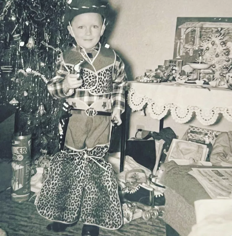 Cute cowboy in front of a Christmas tree