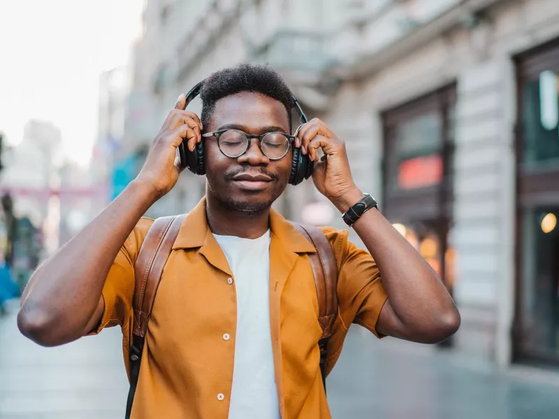 Cheerful young man listening to music while walking on the street.