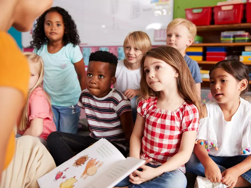 Children listening to their teacher reading a book