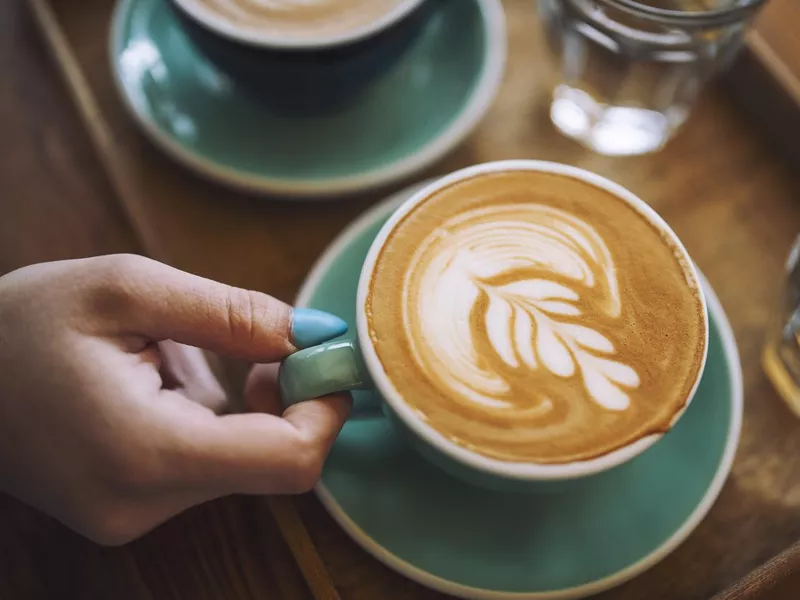 Woman holding a cup of cafe latte in cafe