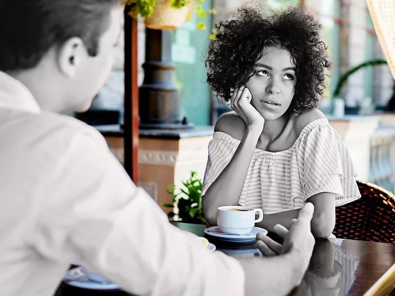 Black woman disinterested with blind date outdoors