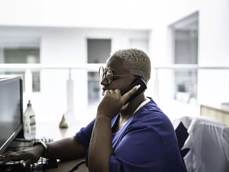 Woman talking on telephone at hospital reception