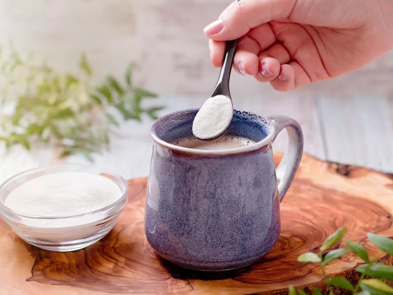 Woman adding collagen powder to her morning coffee. Beauty collagen supplement, additional collagen intake