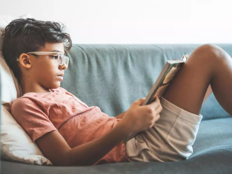 Boy reading book on sofa