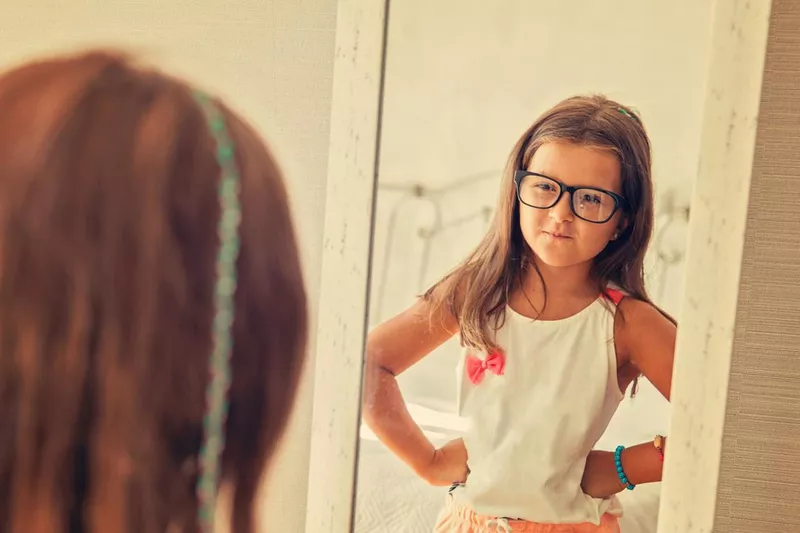 Confident little girl looking in the mirror