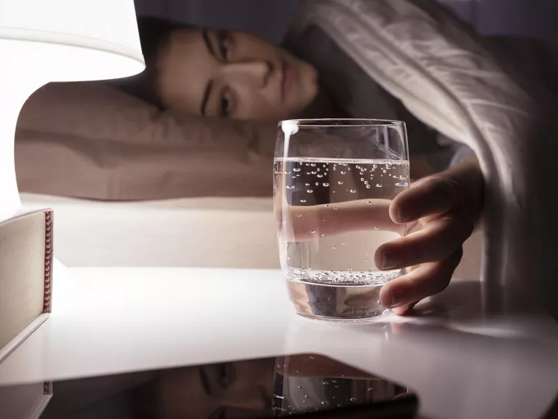 Woman drinking a glass of water at night