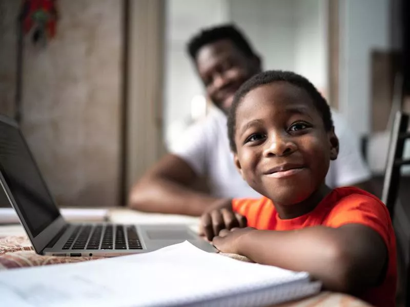 Portrait of father and son studying with laptop on a online class at home