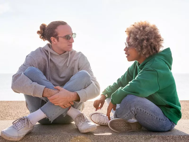 young couple chatting at sunset seated on a bench