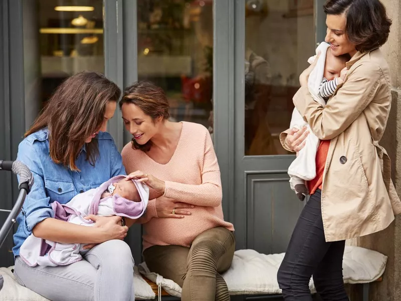 Woman looking at friends playing with baby