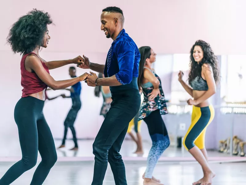 Couple dancers practicing in studio, holding hands