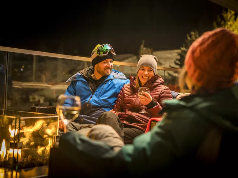 Friends sitting by fire at ski apres at night.