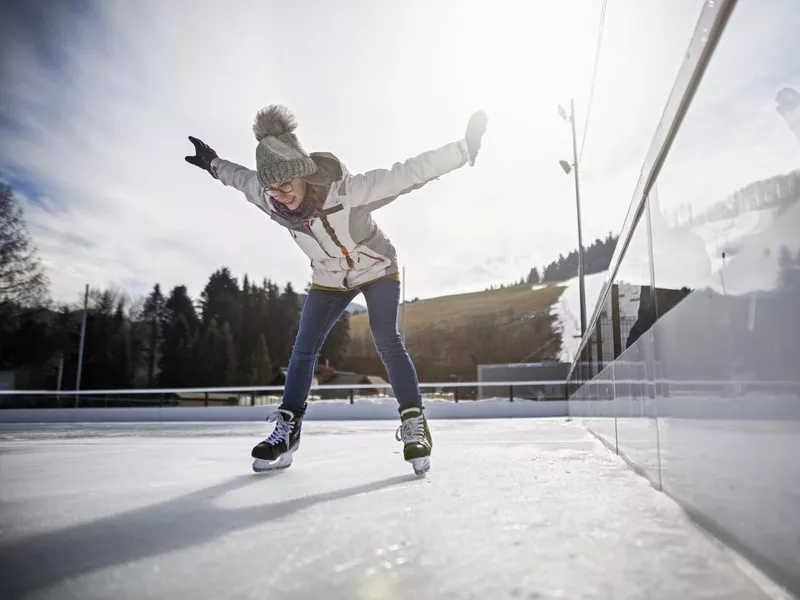 Teenage girl learning to ice skate on outdoors ice rink