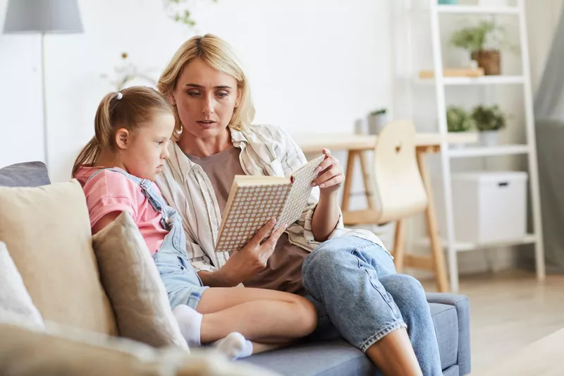 Girl reading a book with her mother