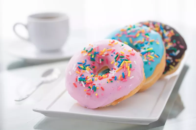 Pink, blue, chocolate sprinkle donuts with a cup of coffee