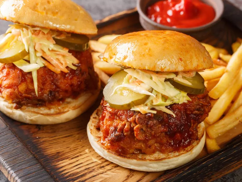 Spicy southern style fried chicken sandwich with coleslaw and pickles closeup on the tray. Horizontal