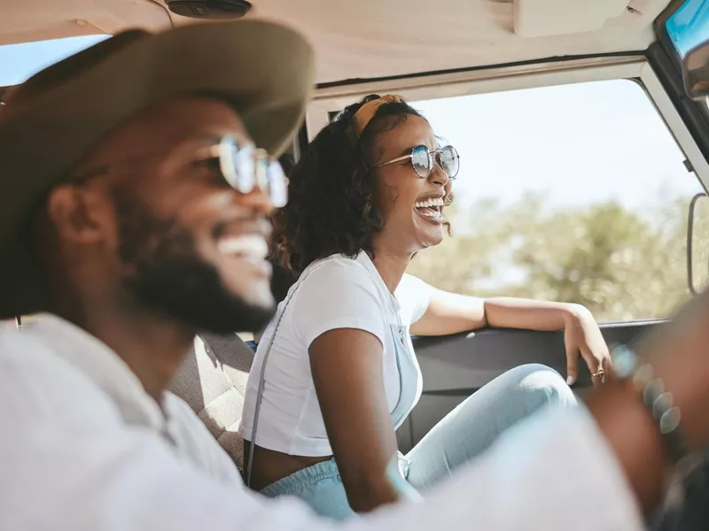 Travel, road trip and black people couple driving by countryside for holiday, journey and freedom with happiness. Trendy sunglasses, fashion and gen z friends in a car drive for vacation lifestyle