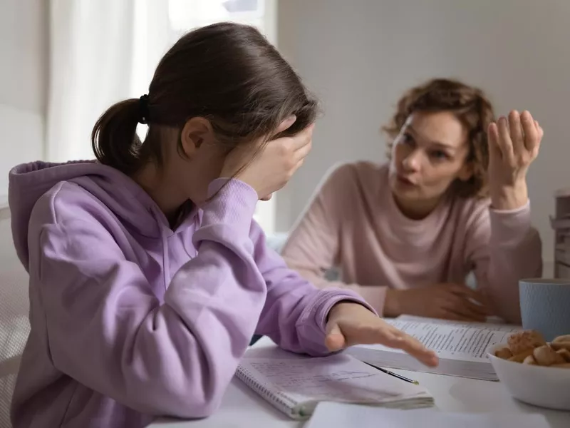 Angry mother scolding lazy teen daughter for bad school results