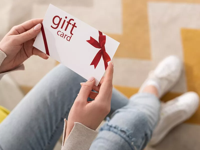 Cropped view of girl holding gift card with red bow