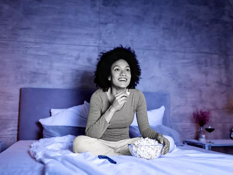 Woman eating popcorn in bed