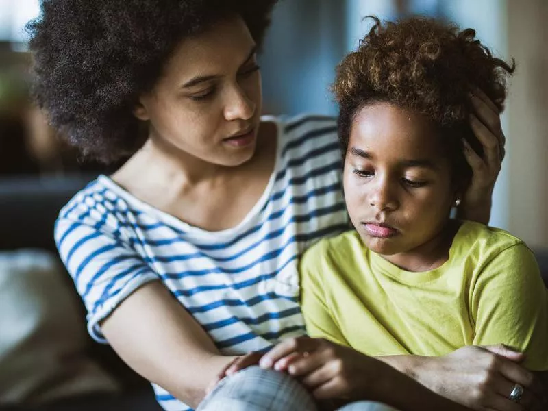 African American mother consoling her sad girl at home.