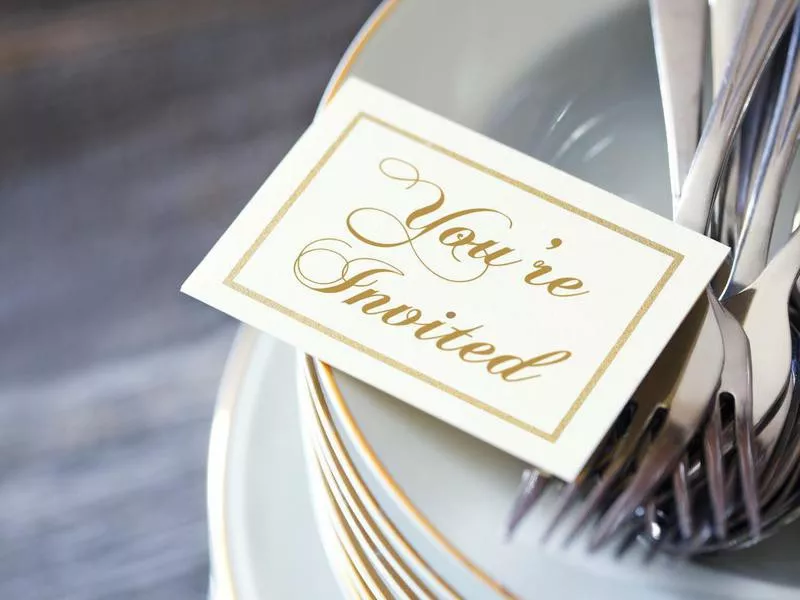 Invitation Resting On Top Of Stack Of Dinner Plates