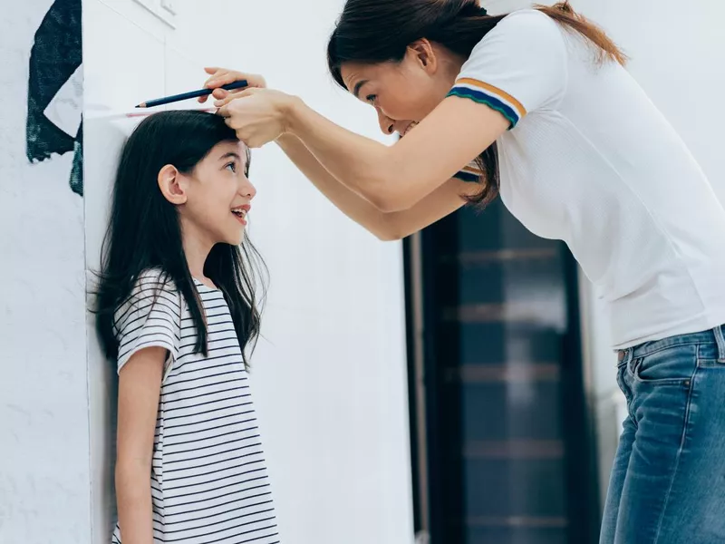 Mom measuring the growth of her daughter