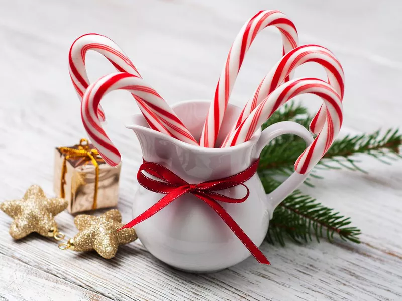 Jug with christmas candy canes on a wooden table