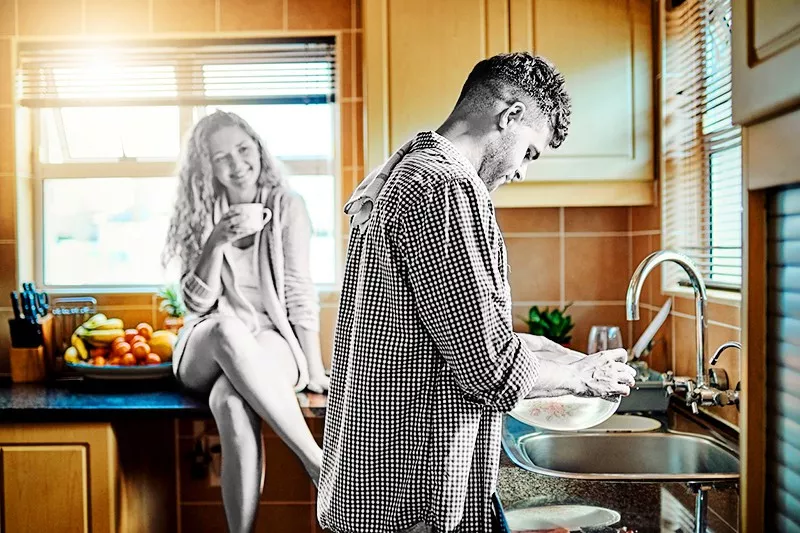 Woman keeping her husband company while he does the dishes