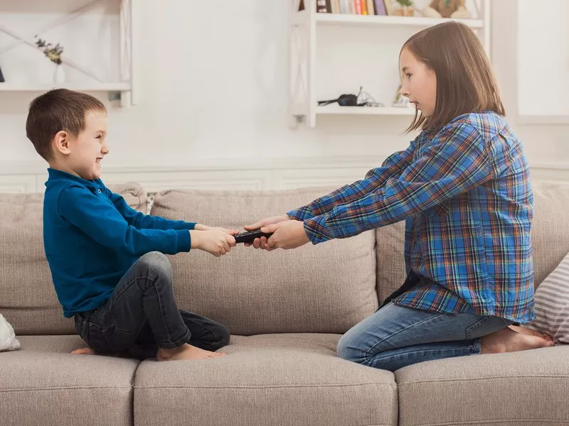 Siblings fighting over remote control at home