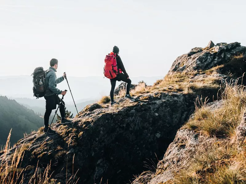 Young couple backpack up a mountain summit