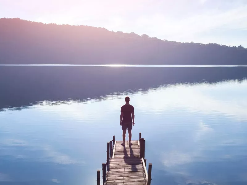 Man looking out over a peaceful lake