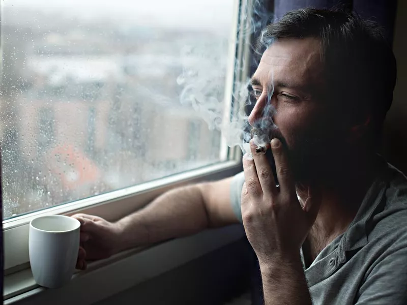 Man smoking by a window