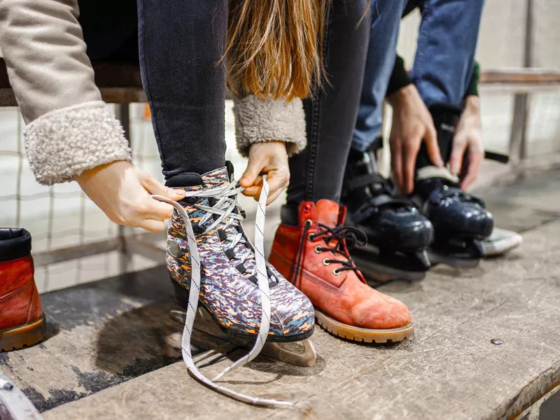 Young couple tying laces on their ice skates