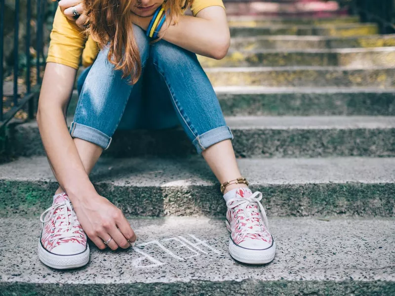 Unhappy girl writes help on the ground