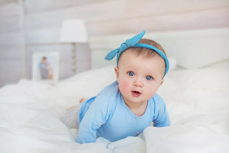 Smiling infant crawling on a bed