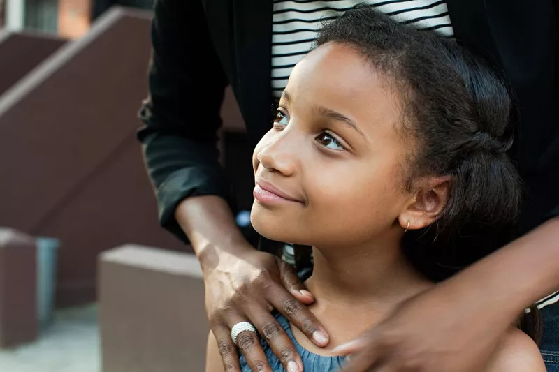 Girl standing with mother, looking away