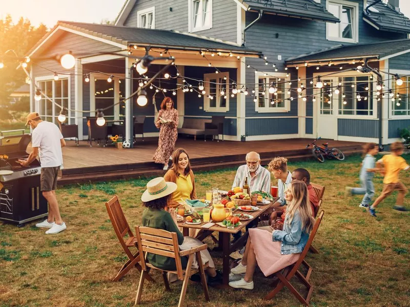 Big Family and Friends Celebrating Outside at Home. Diverse Group of Children, Adults and Old People Gathered at a Table, Having Fun Conversations. Preparing Barbecue and Eating Vegetables.